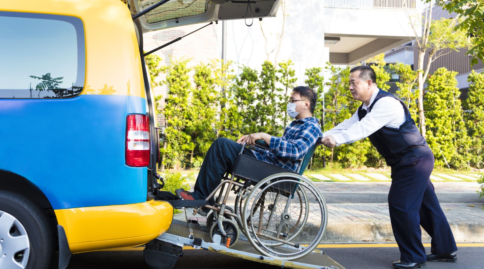 driver helping man on wheelchair getting into taxi